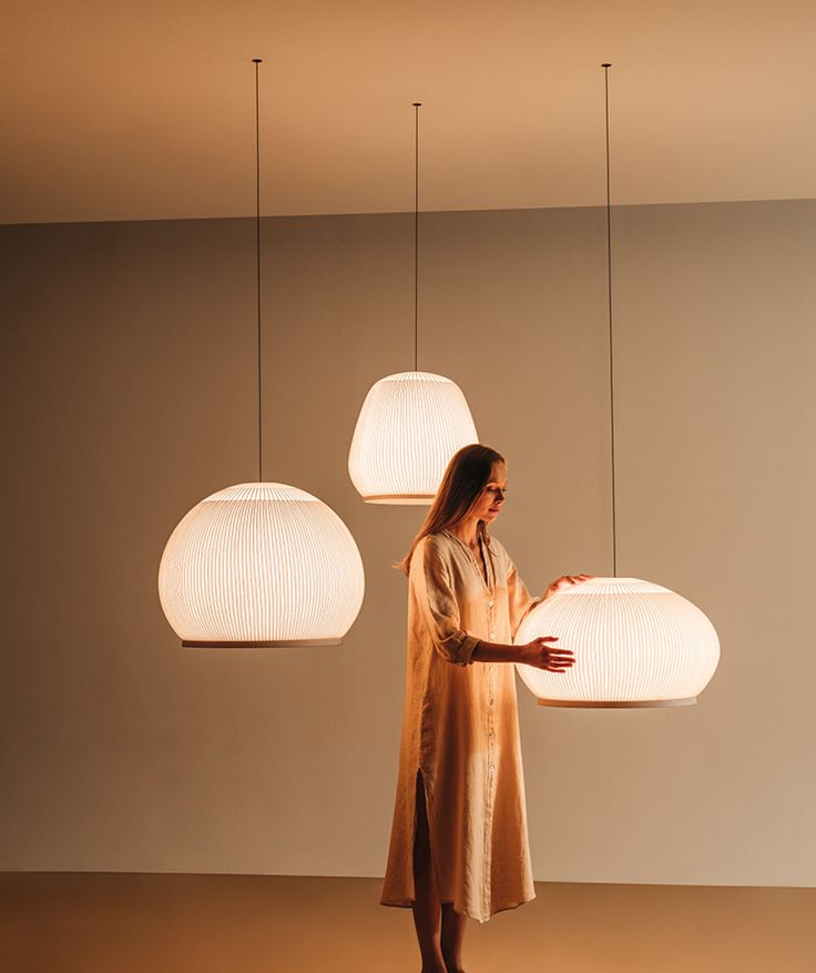 a woman standing in front of three hanging lights