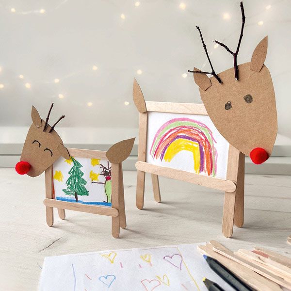 two wooden reindeer standing next to each other on top of a white table with markers and pencils