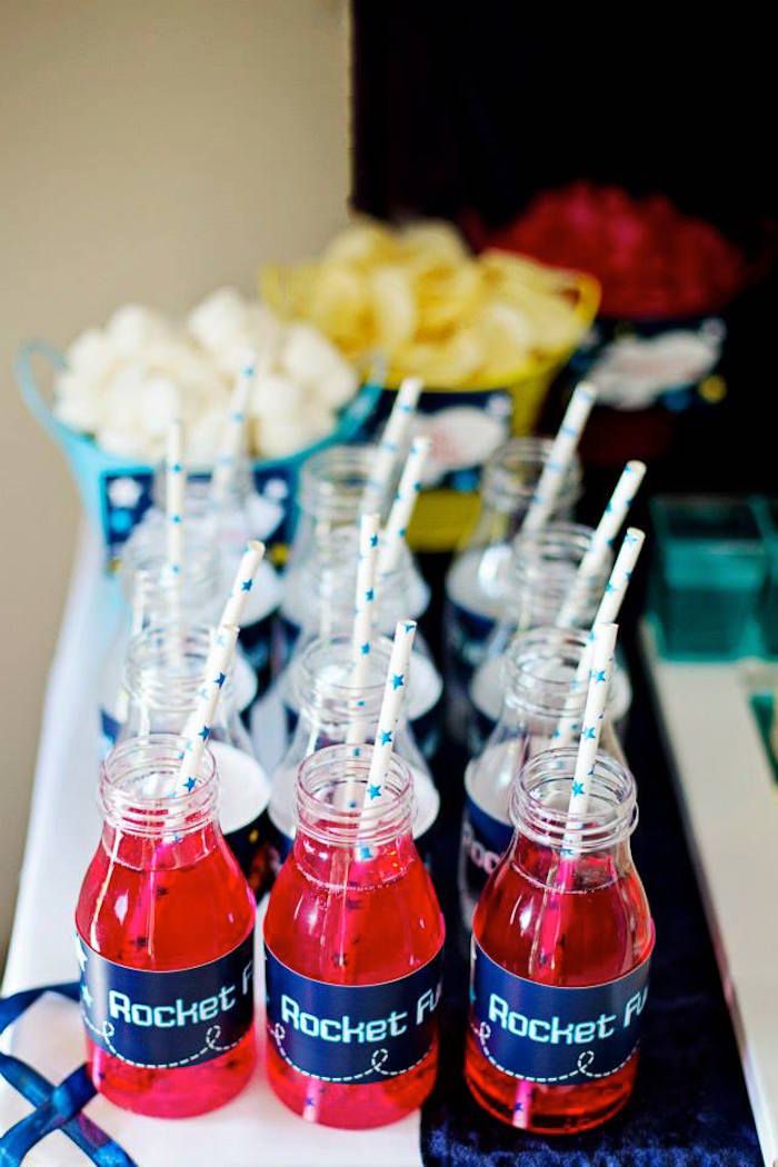 red drinks are lined up on a table with blue and white napkins in front of them