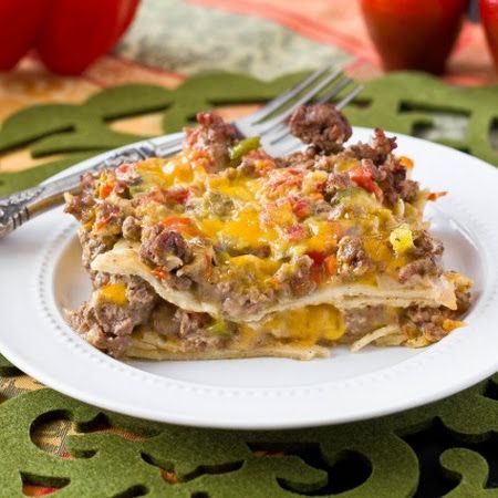 a white plate topped with lasagna covered in meat and cheese next to an apple