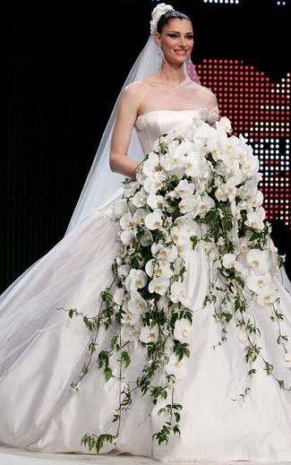 a woman in a wedding dress with flowers on the runway