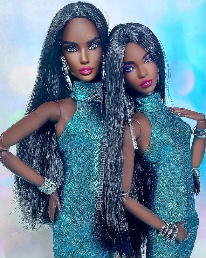 two dolls are posed in front of a blue background