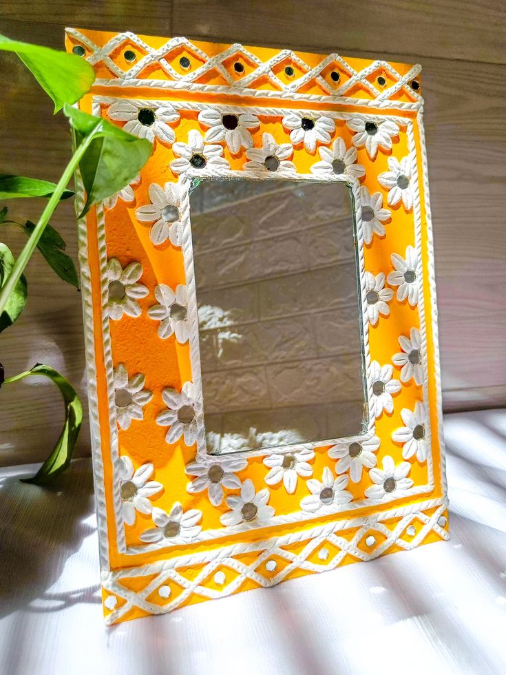 an orange and white mirror sitting on top of a table next to a potted plant