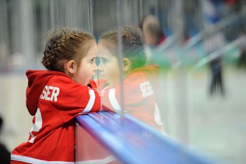 two young children are looking out the window at an ice hockey rink while people watch