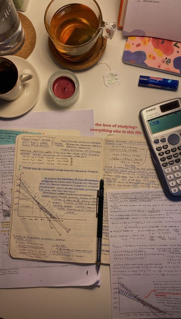 a table topped with papers and a calculator next to a cup of coffee