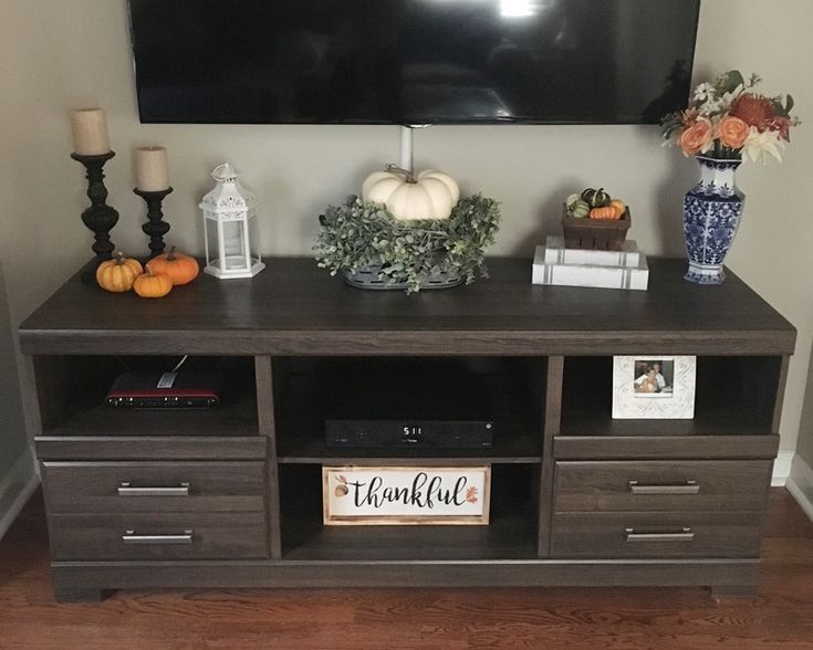 a flat screen tv sitting on top of a wooden entertainment center next to a vase filled with flowers