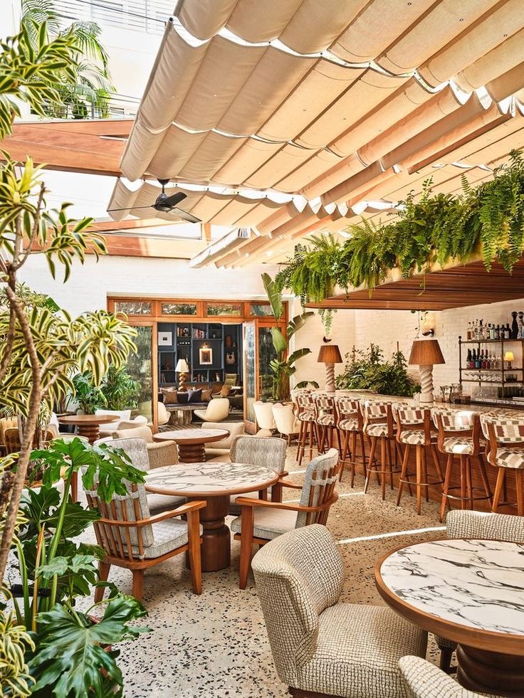 a restaurant with tables, chairs and plants on the ceiling is shown in this image