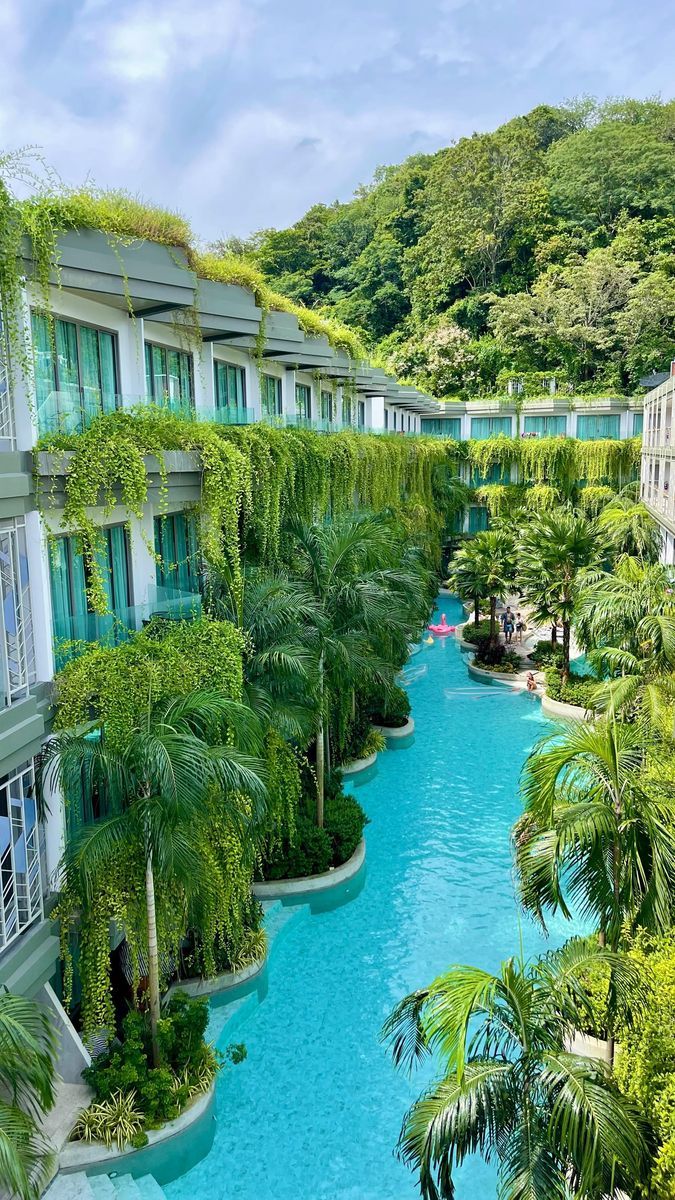 an outdoor swimming pool surrounded by palm trees and apartment buildings with balconies on each side