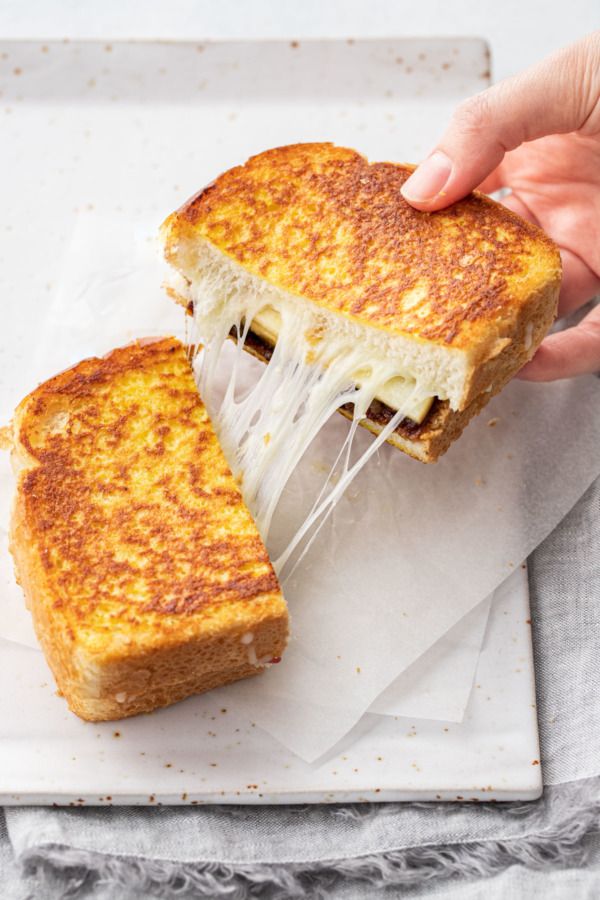 someone is holding up a grilled cheese sandwich with melted cheese on the top and bottom