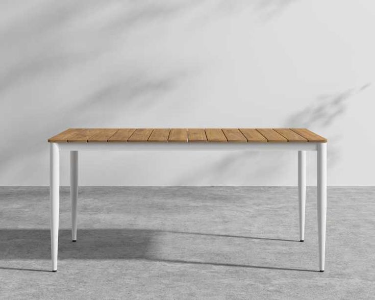 a wooden table with white legs and a wood top on concrete floor in an empty room