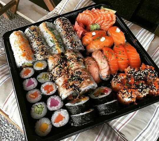 an assortment of sushi on a black tray