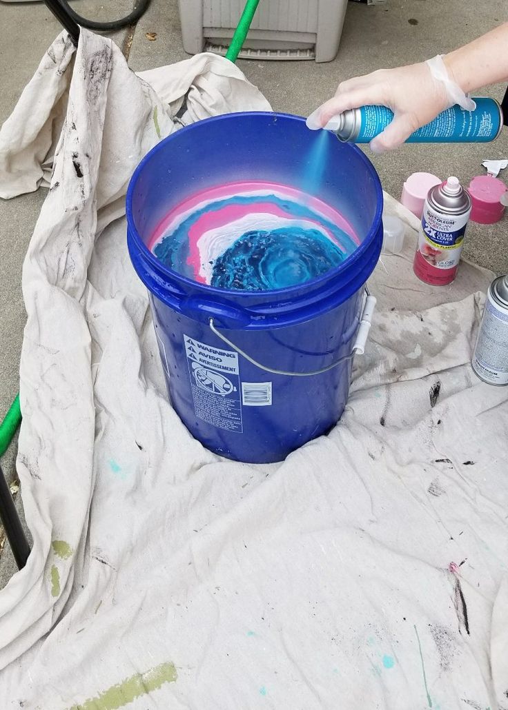 someone is painting the inside of a bucket with blue and pink paint on it,