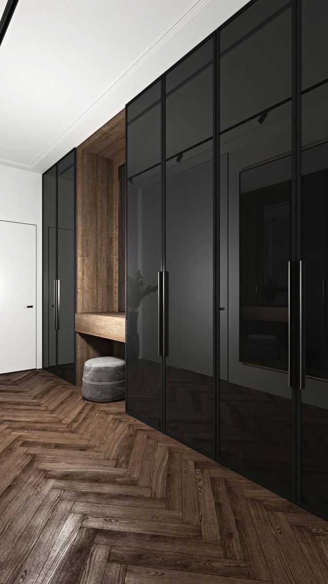 an empty room with wooden flooring and black glass doors on either side of the closet