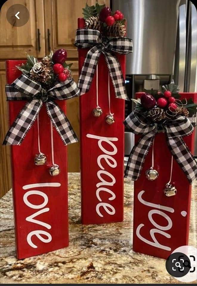 two red wooden signs with christmas decorations on them sitting on top of a kitchen counter