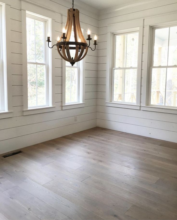 an empty room with two windows and a chandelier hanging from the ceiling in it