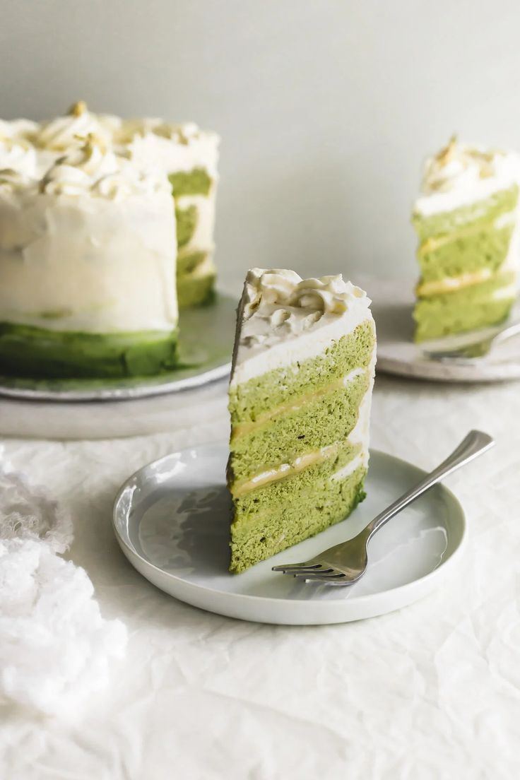 a slice of green cake with white frosting on a plate and another piece is missing