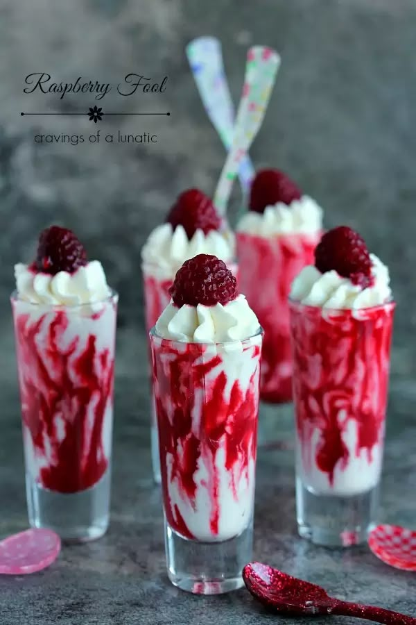 raspberry trifle with whipped cream and strawberries in shot glasses on table