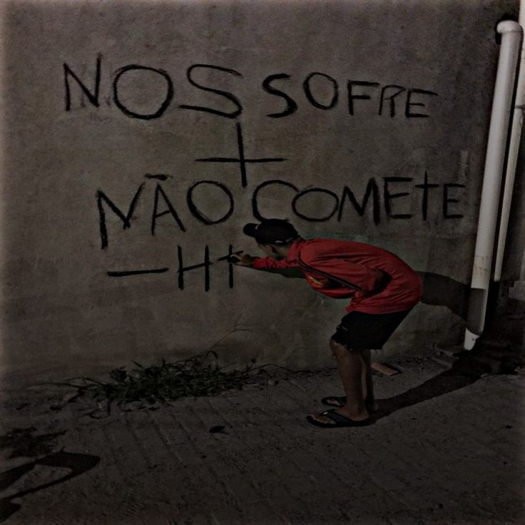 a man writing graffiti on the side of a wall with words written in black ink