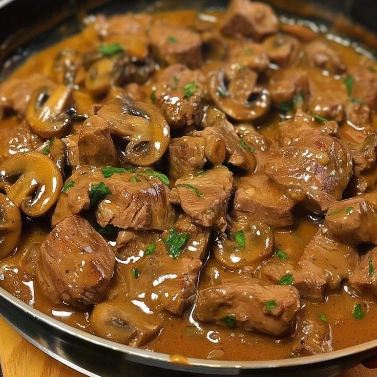 meat and mushrooms in gravy on a pan