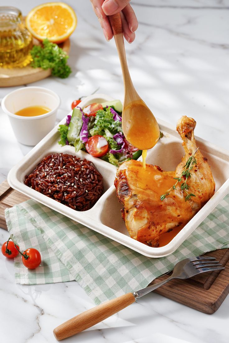 a person holding a wooden spoon with food in it on a tray next to other dishes