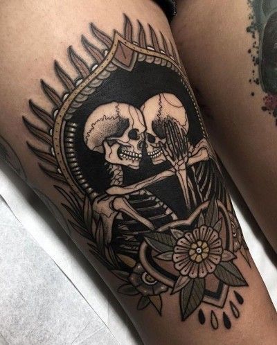 a couple of skulls sitting on top of each other in front of a woman's thigh