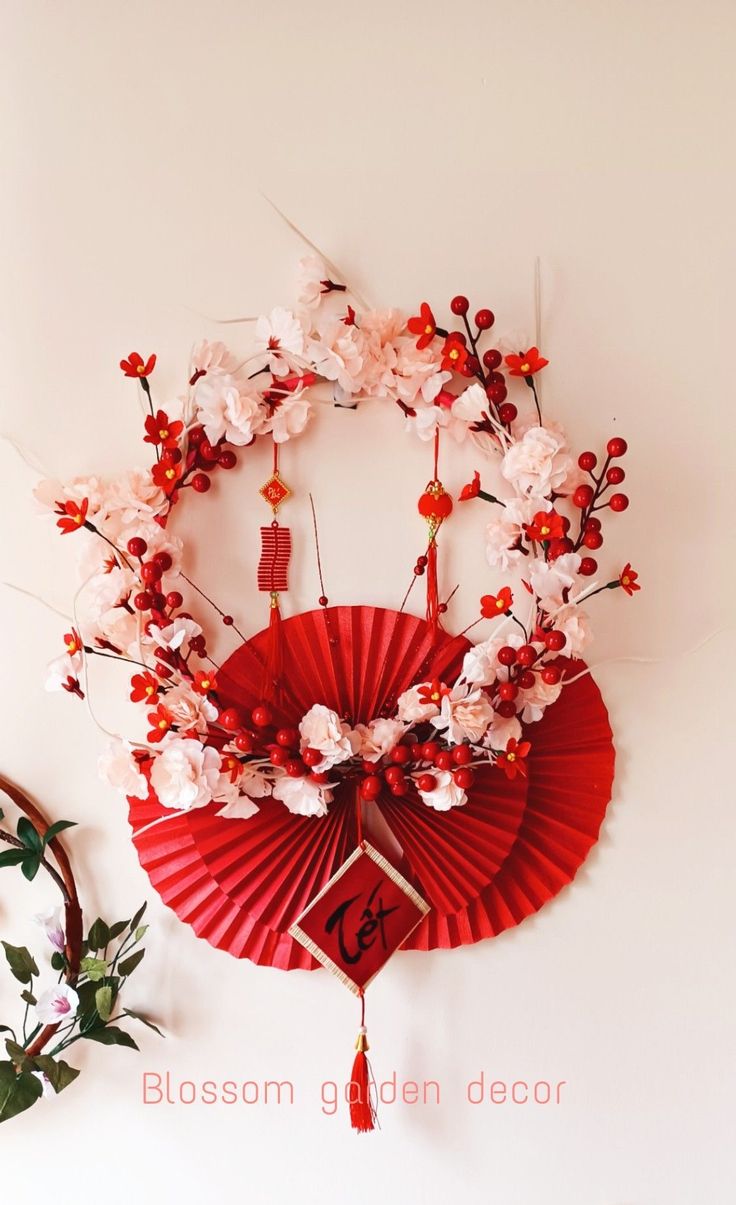 a red fan with white flowers on it and a clock hanging from the wall behind it