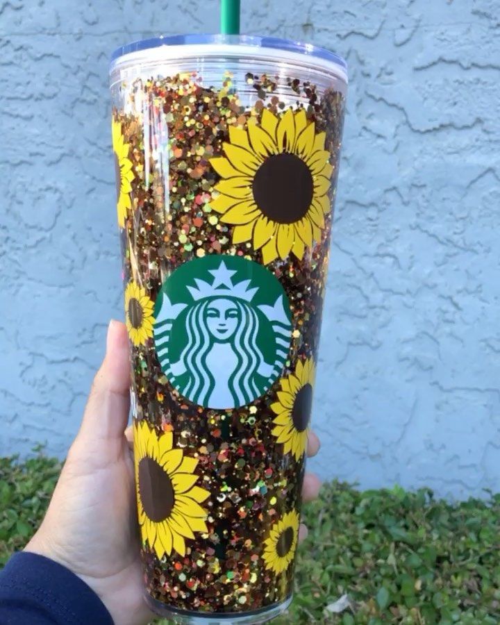 someone holding up a starbucks cup with sunflowers and sprinkles on it