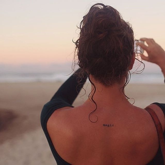 the back of a woman's head with a small tattoo on her left shoulder