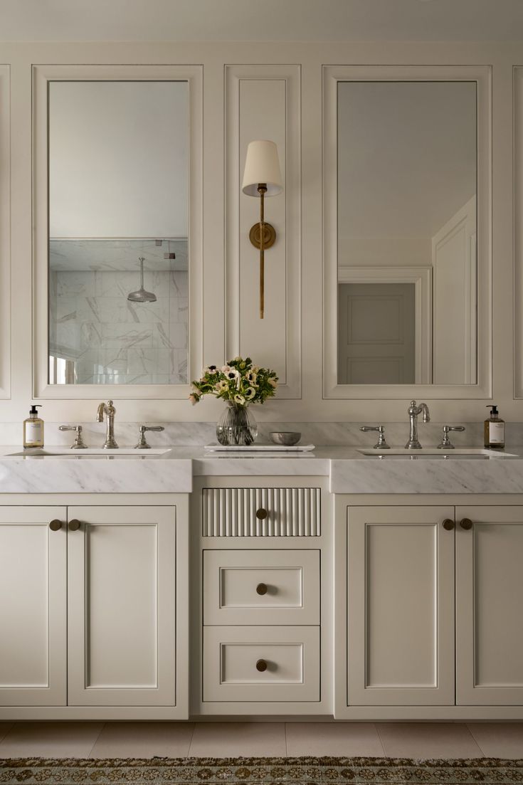 a bathroom with two sinks and mirrors on the wall next to each other in white cabinets