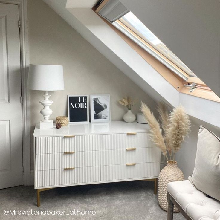 a white dresser sitting under a slanted roof