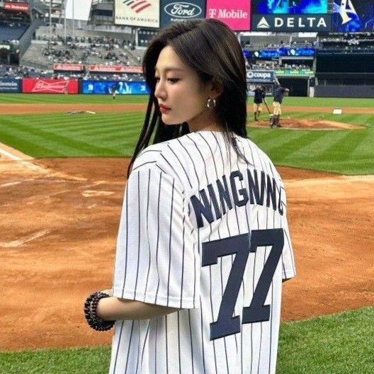 a woman standing on top of a baseball field wearing a uniform and holding a glove