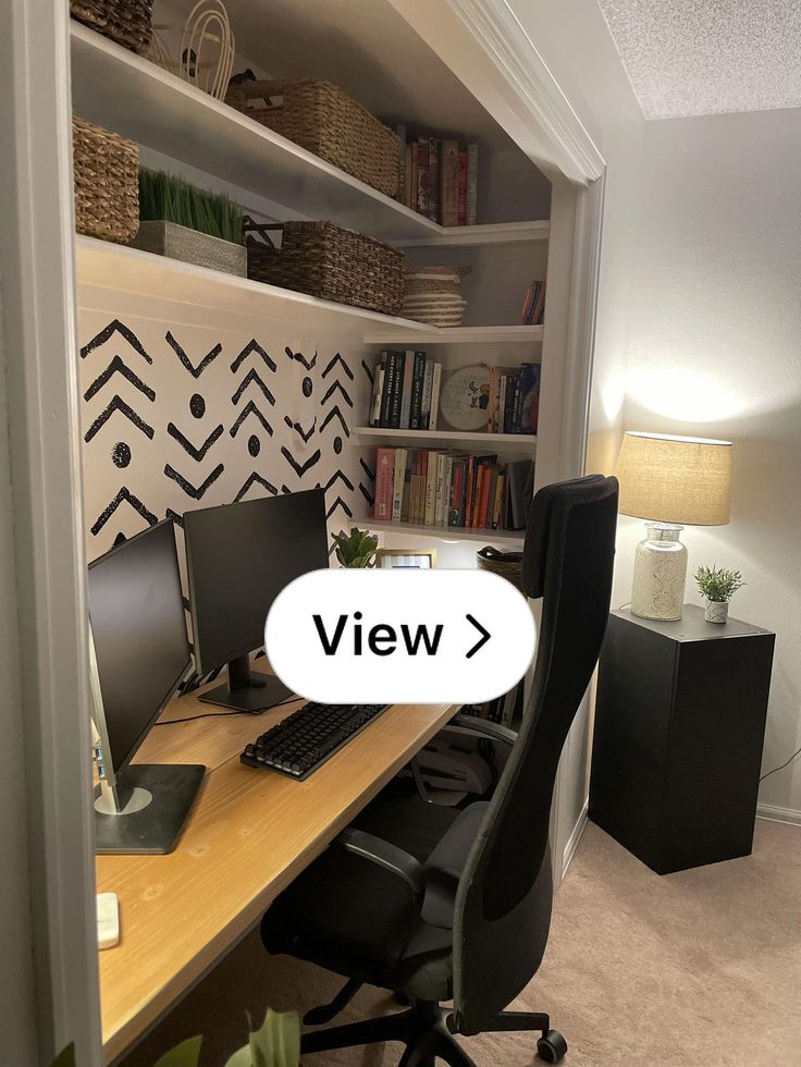 a desk with a computer on it in front of a bookshelf