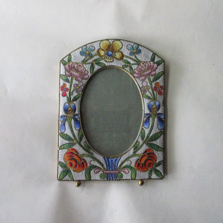 a decorative mirror with flowers on it sitting on a white surface next to a wall