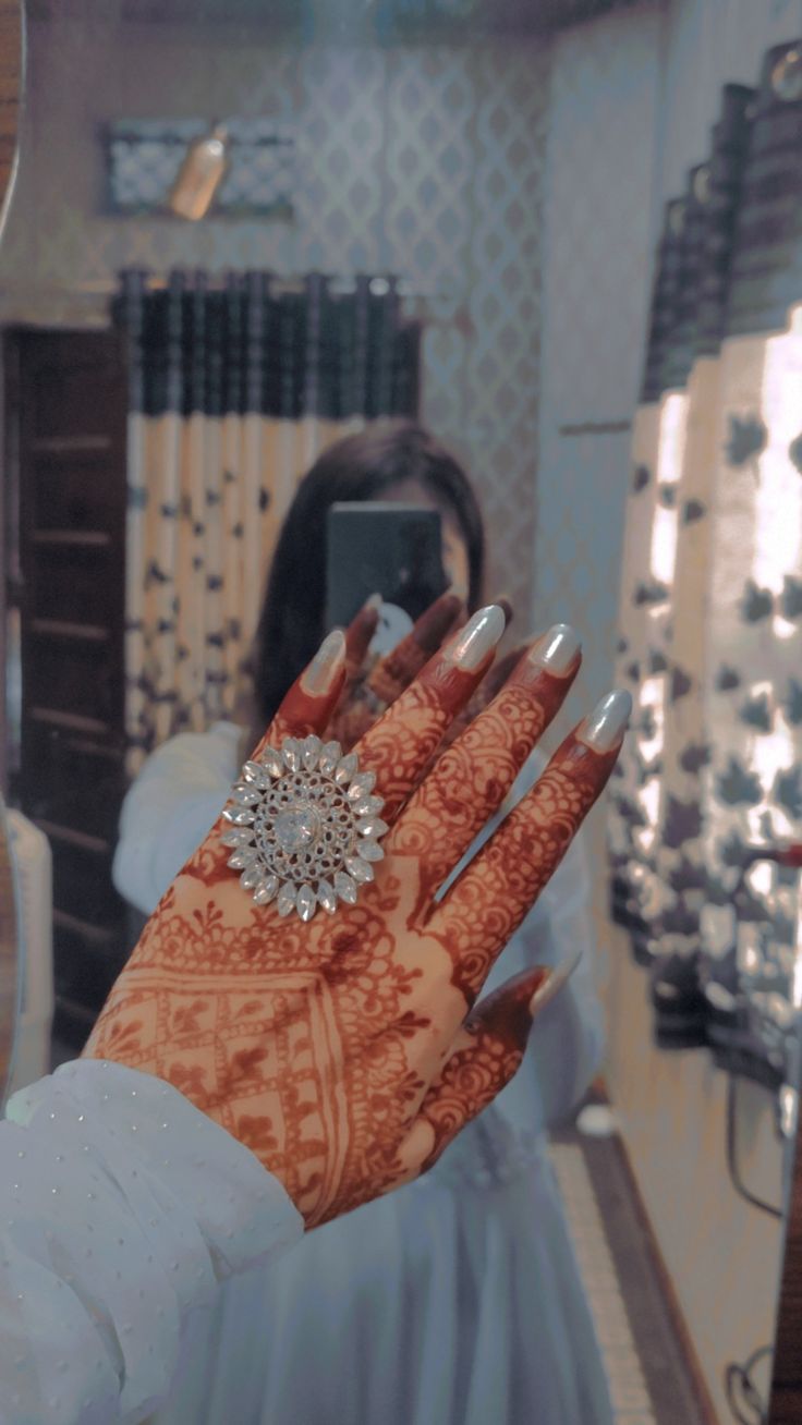 a woman's hand with henna on it in front of a mirror