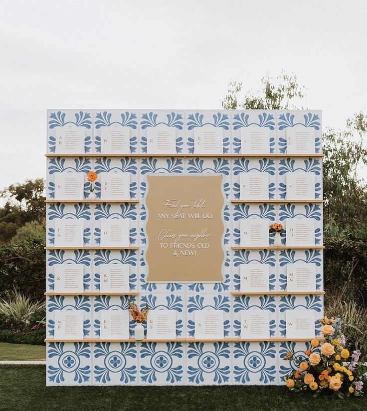 a blue and white wall with flowers on the side, next to a sign that reads