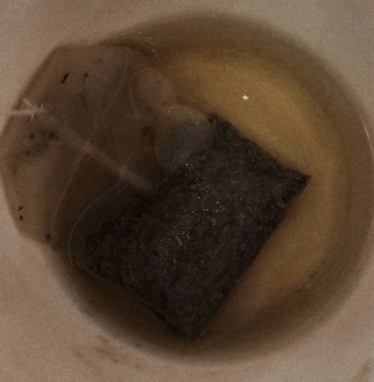 a white bowl filled with brown liquid next to a black object on top of a table