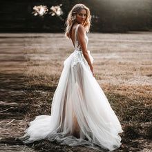 a woman standing in a field wearing a wedding dress with sheer tulle and open back