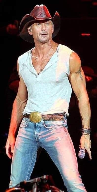 a man in jeans and a cowboy hat is on stage with his arms out to the side