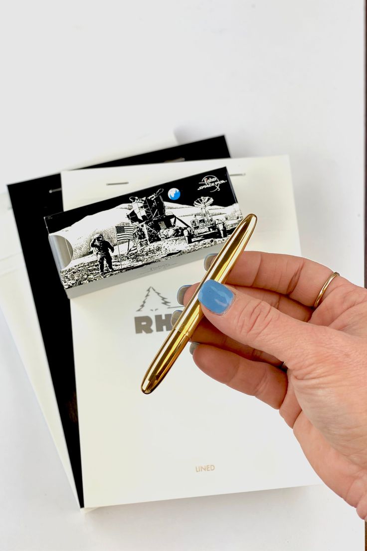 a person holding a pen in their left hand and some photos on the wall behind them