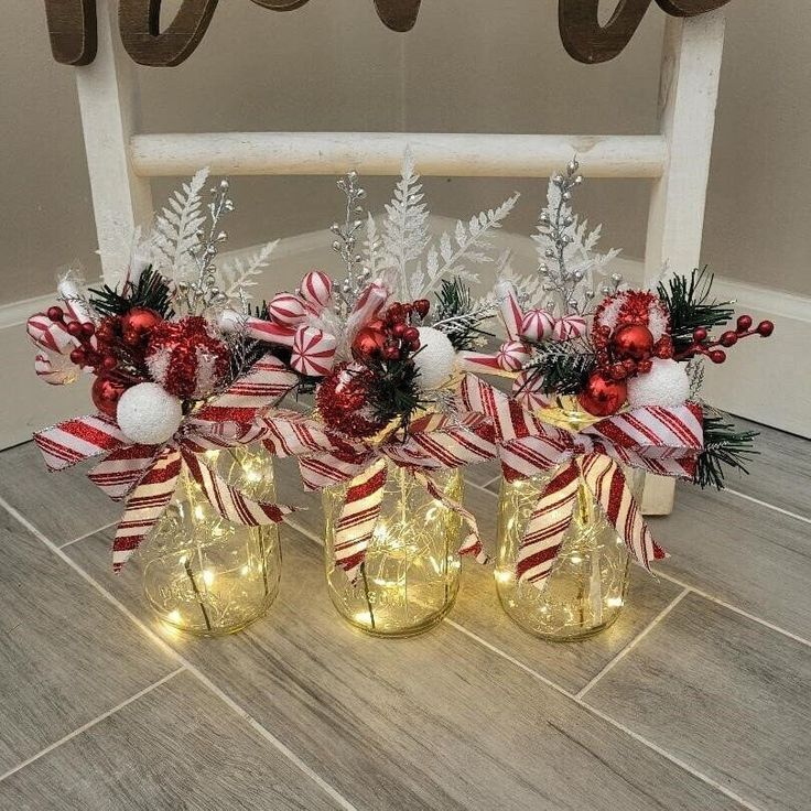 three wine glasses with candy canes and lights in them sitting on the floor next to christmas decorations