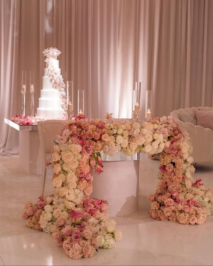 a table with flowers and candles on it in front of a wedding cake at a reception