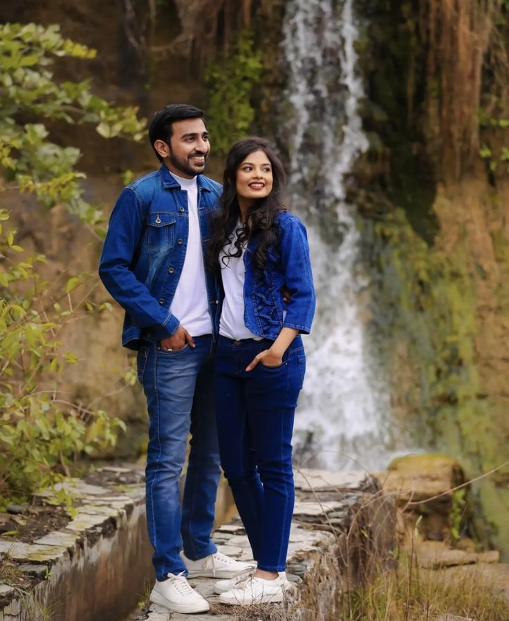 a man and woman standing next to a waterfall