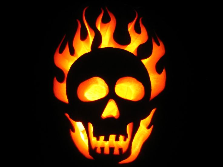 a carved pumpkin with flames in the shape of a skull