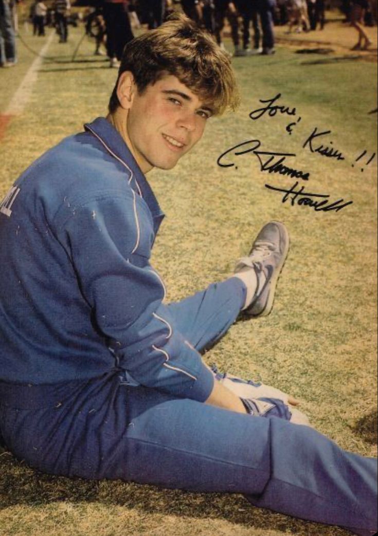 a baseball player sitting on the ground with his feet up and hands in his pockets