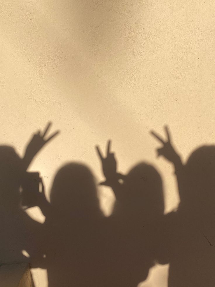 the shadow of three people holding their hands up