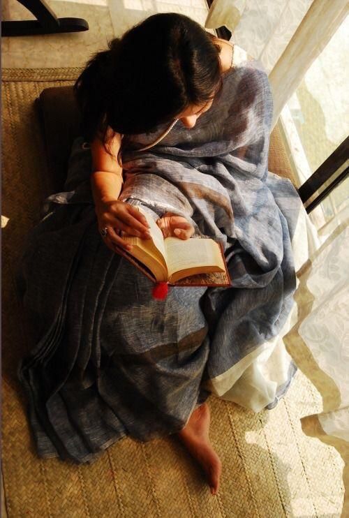 a woman sitting on the floor reading a book