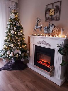 a decorated christmas tree sitting in front of a fire place with lights on the mantle