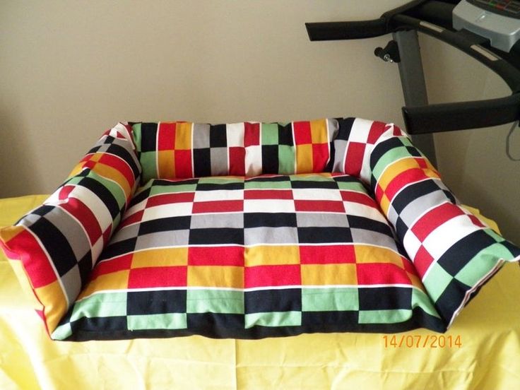 a colorful dog bed on top of a yellow sheet next to a treading machine