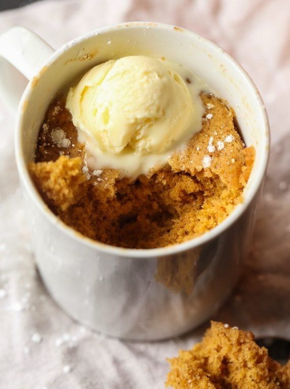 a white cup filled with ice cream next to a piece of breadcrumbs