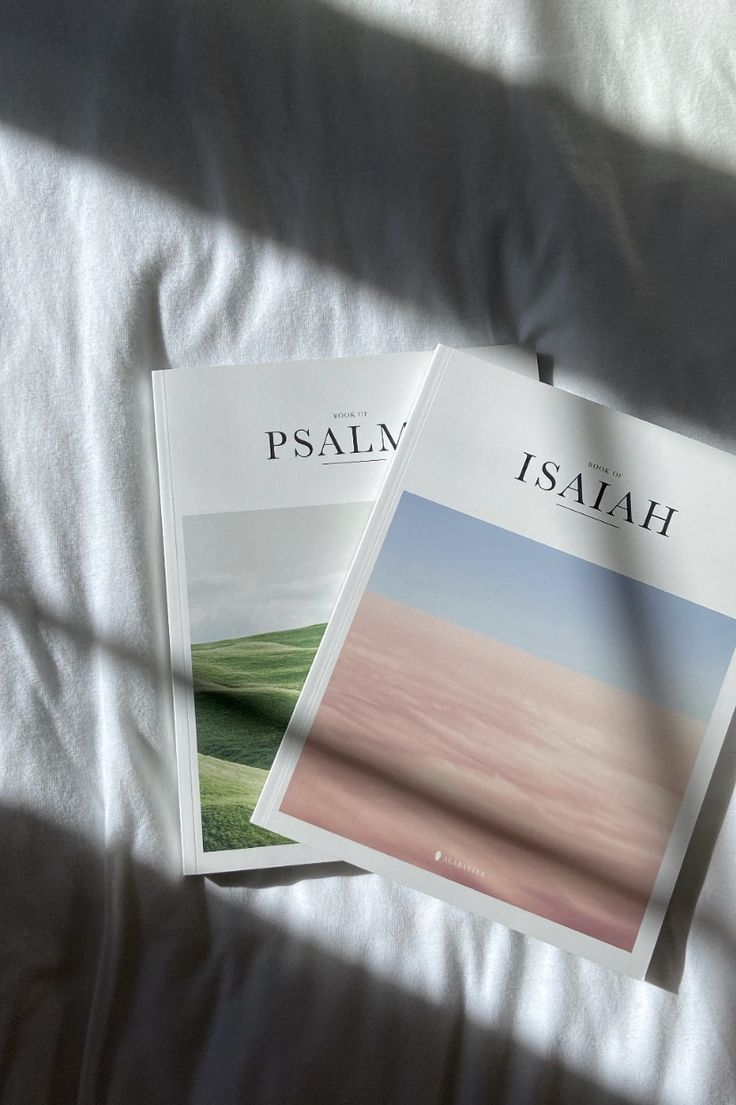 two magazines sitting on top of a bed next to each other